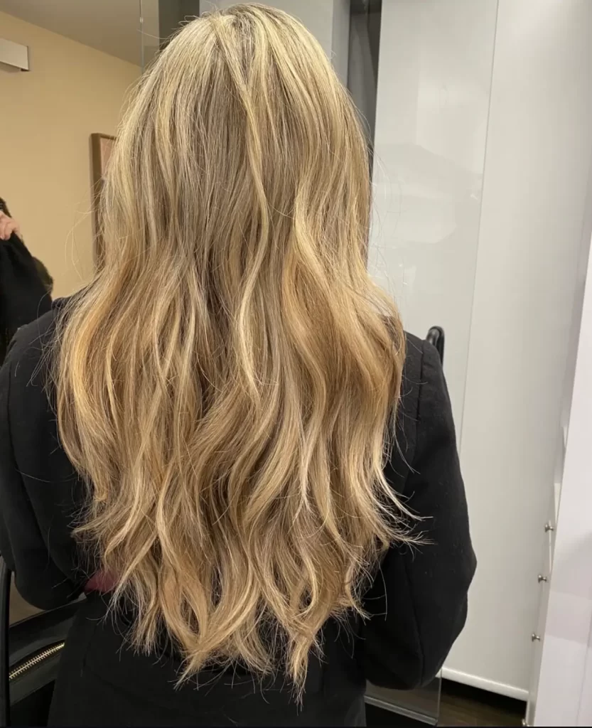 Close up view of a woman's blonde wavy hair. Her back is to us.