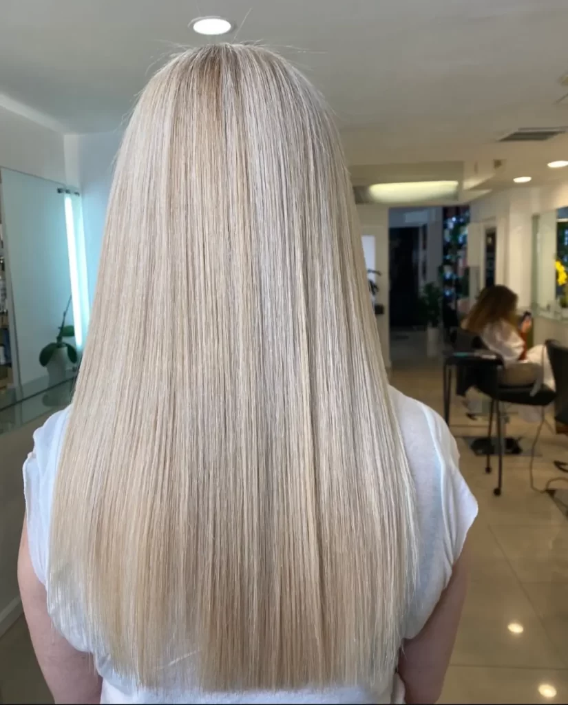 Close up view of a woman's blonde straight hair. Her back is to us.