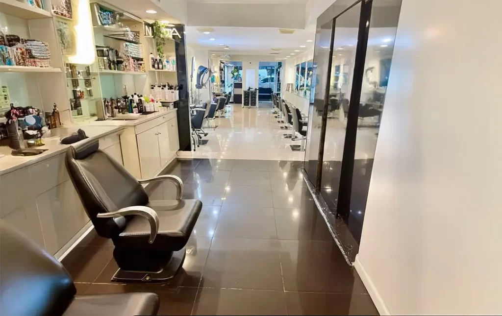 Interior view of a hair salon. We see two chairs to get haircuts in and hair products on top of counters.